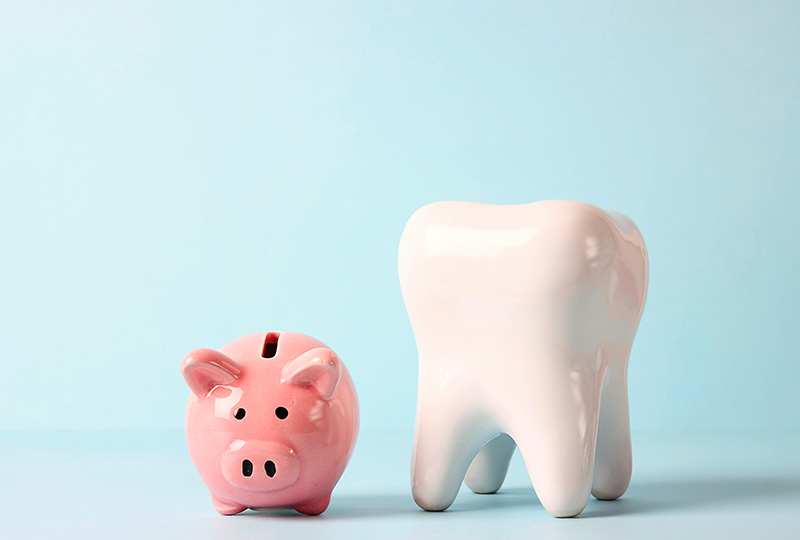 A playful arrangement of a pink piggy bank, a white toothbrush holder shaped like a tooth, and a pink piggy bank with a white toothbrush inside, all set against a blue background.